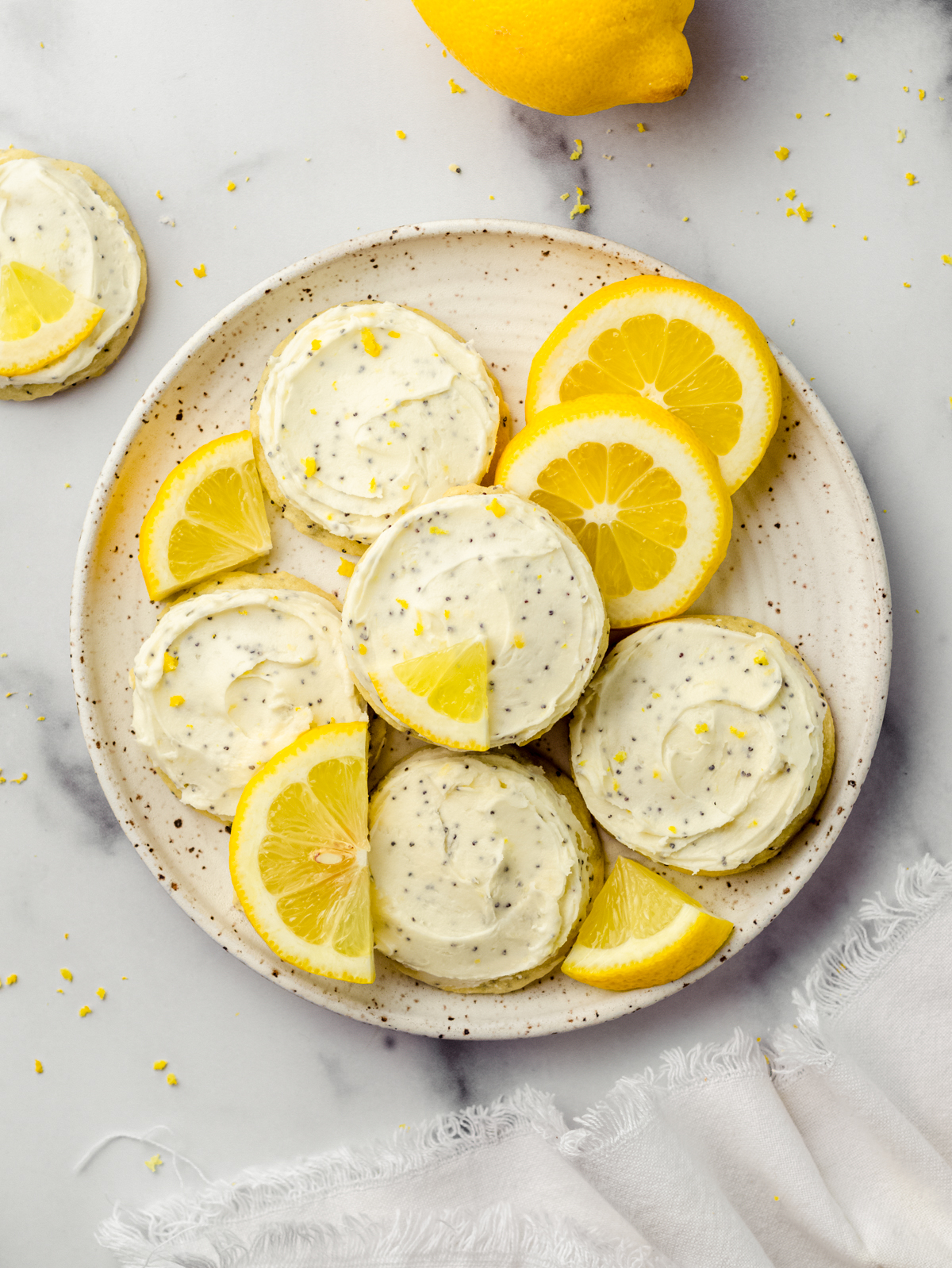 Aerial photo of frosted lemon poppy seed cookies on a plate.