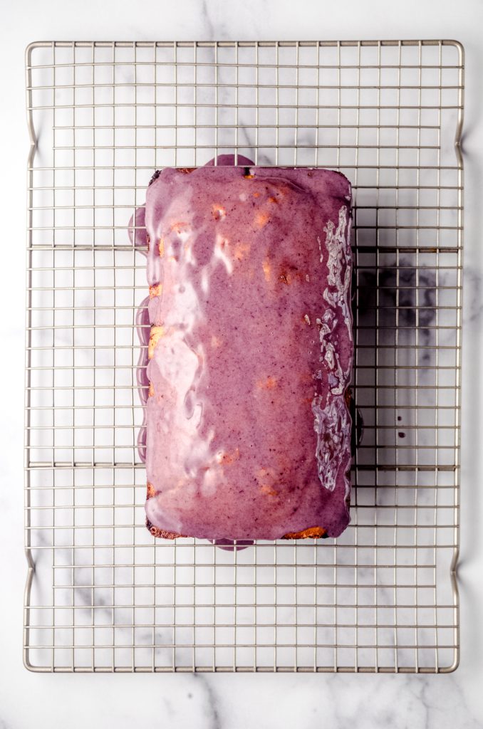 Aerial photo of a loaf of blackberry pound cake on a wire rack.