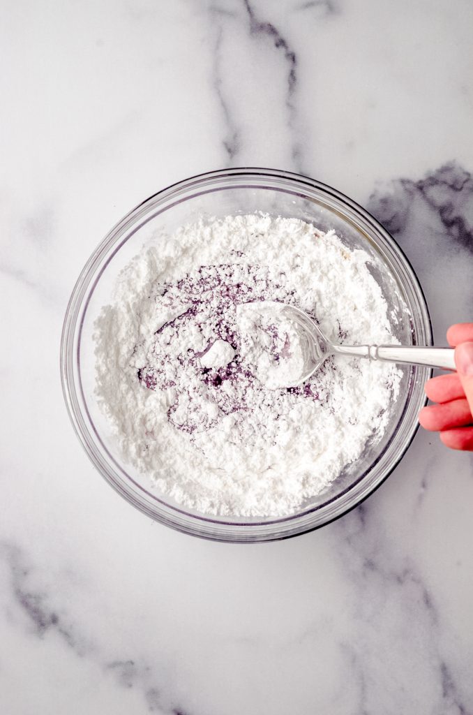 Aerial photo of a bowl of someone stirring ingredients together to make fresh blackberry icing.