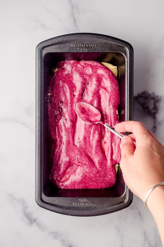 Aerial photo of someone layering blackberry pound cake batter in a loaf pan.
