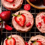 Frosted strawberry cookies on a wire cooling rack.