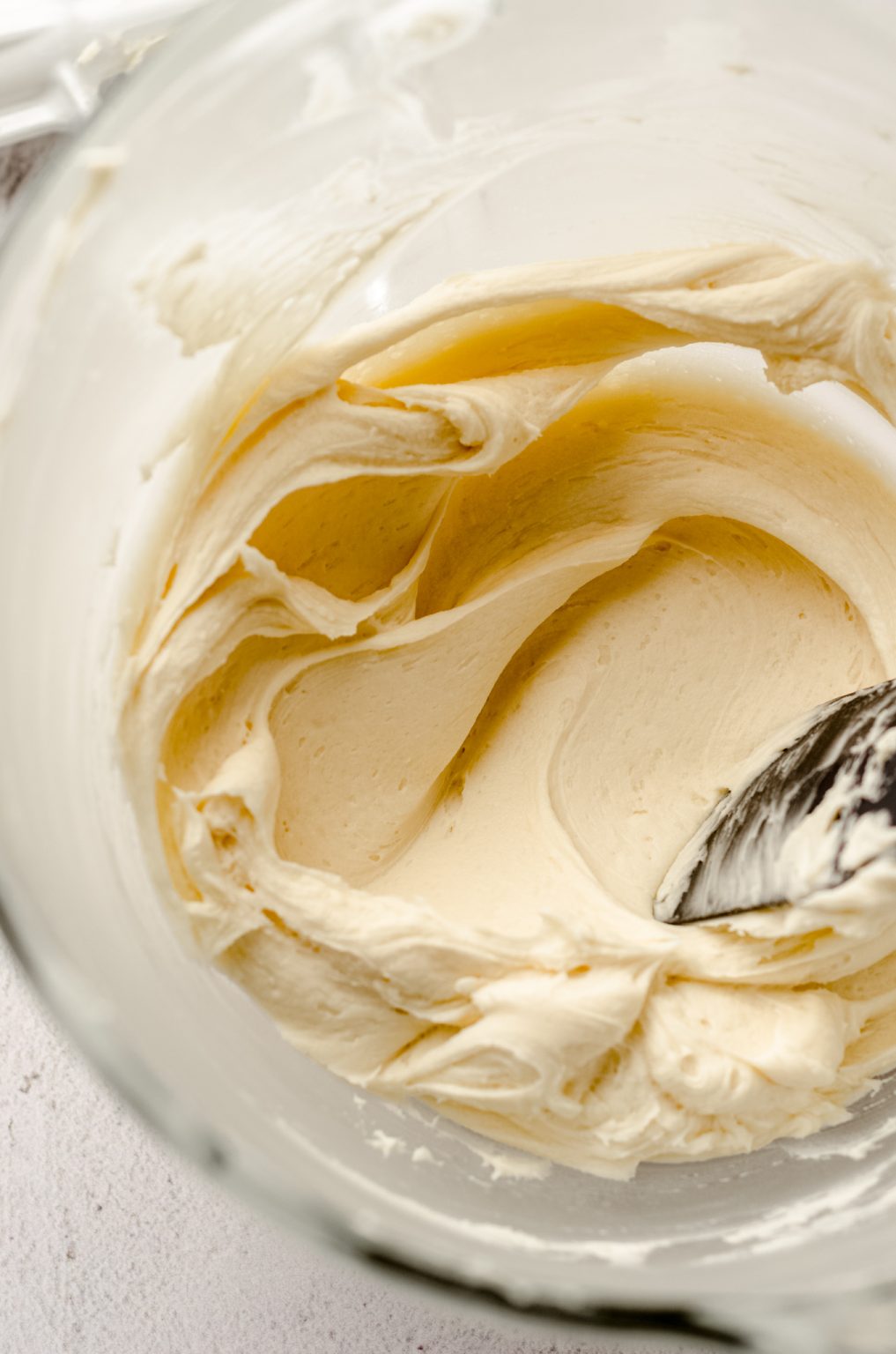 A bowl of smooth vanilla buttercream in a bowl with a spatula.