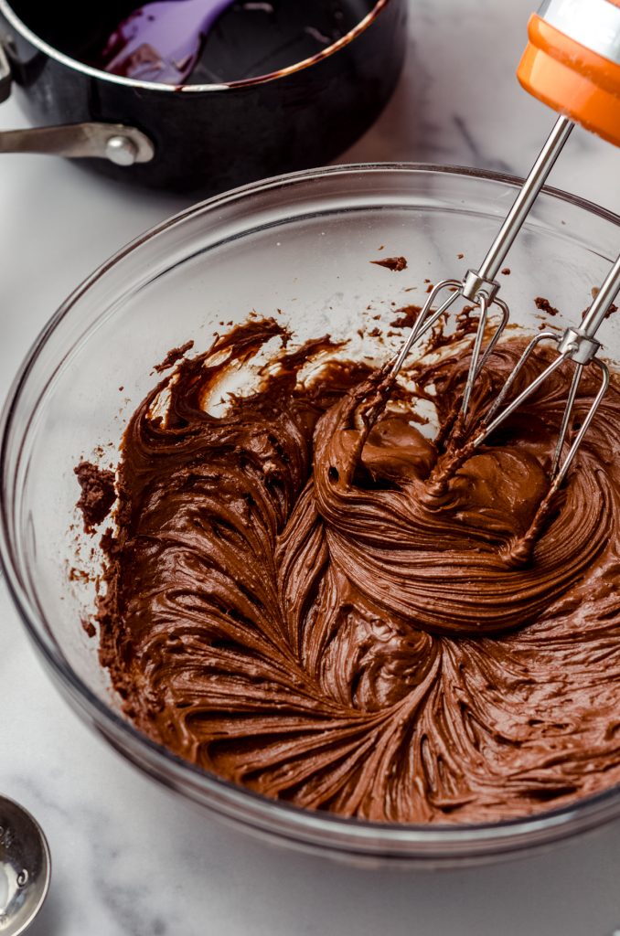 A bowl of chocolate fudge frosting with beaters in it.