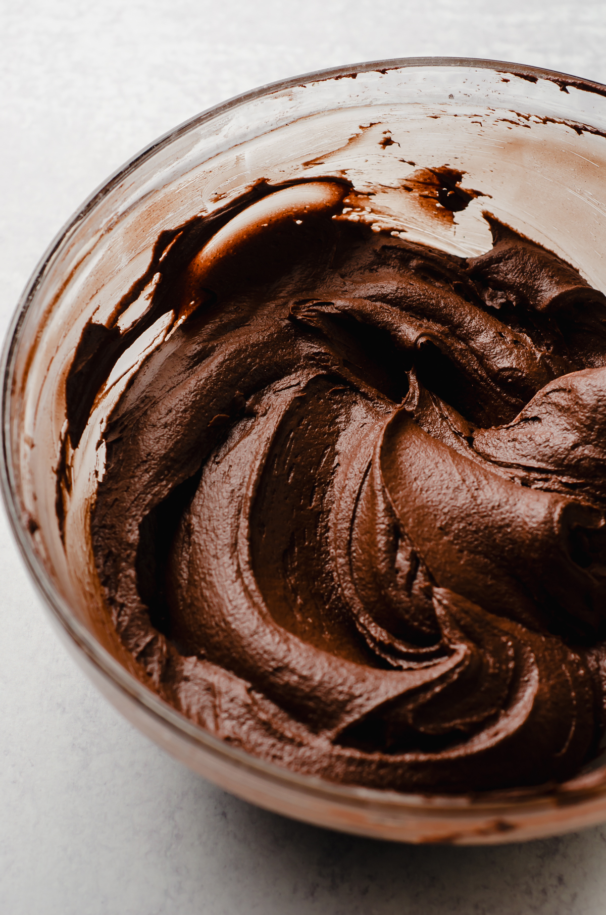 A bowl of chocolate frosting made with cocoa powder in a bowl.