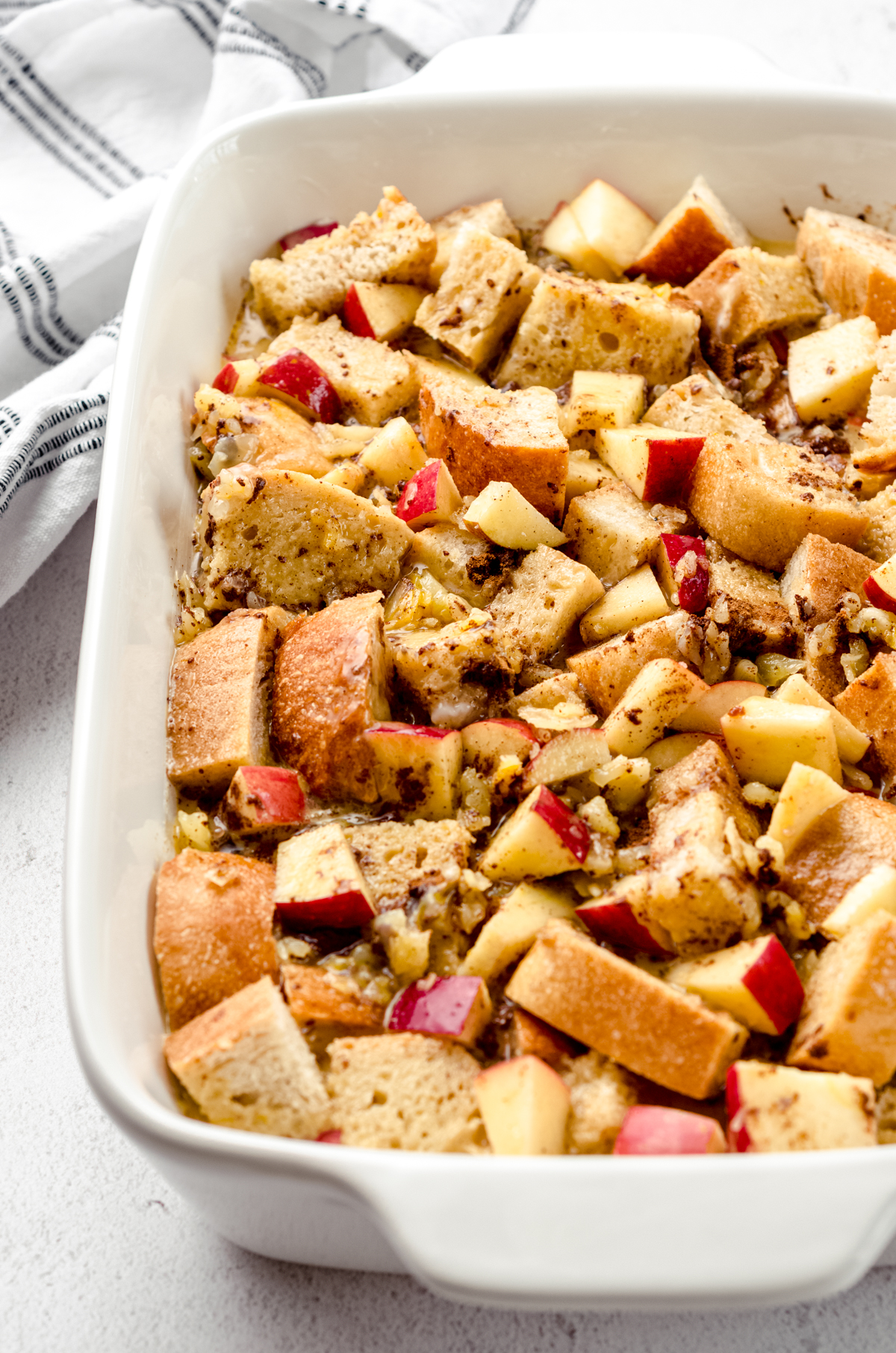 Apples and bread cubes soaking in a cinnamon custard in a casserole dish to make apple French toast casserole.
