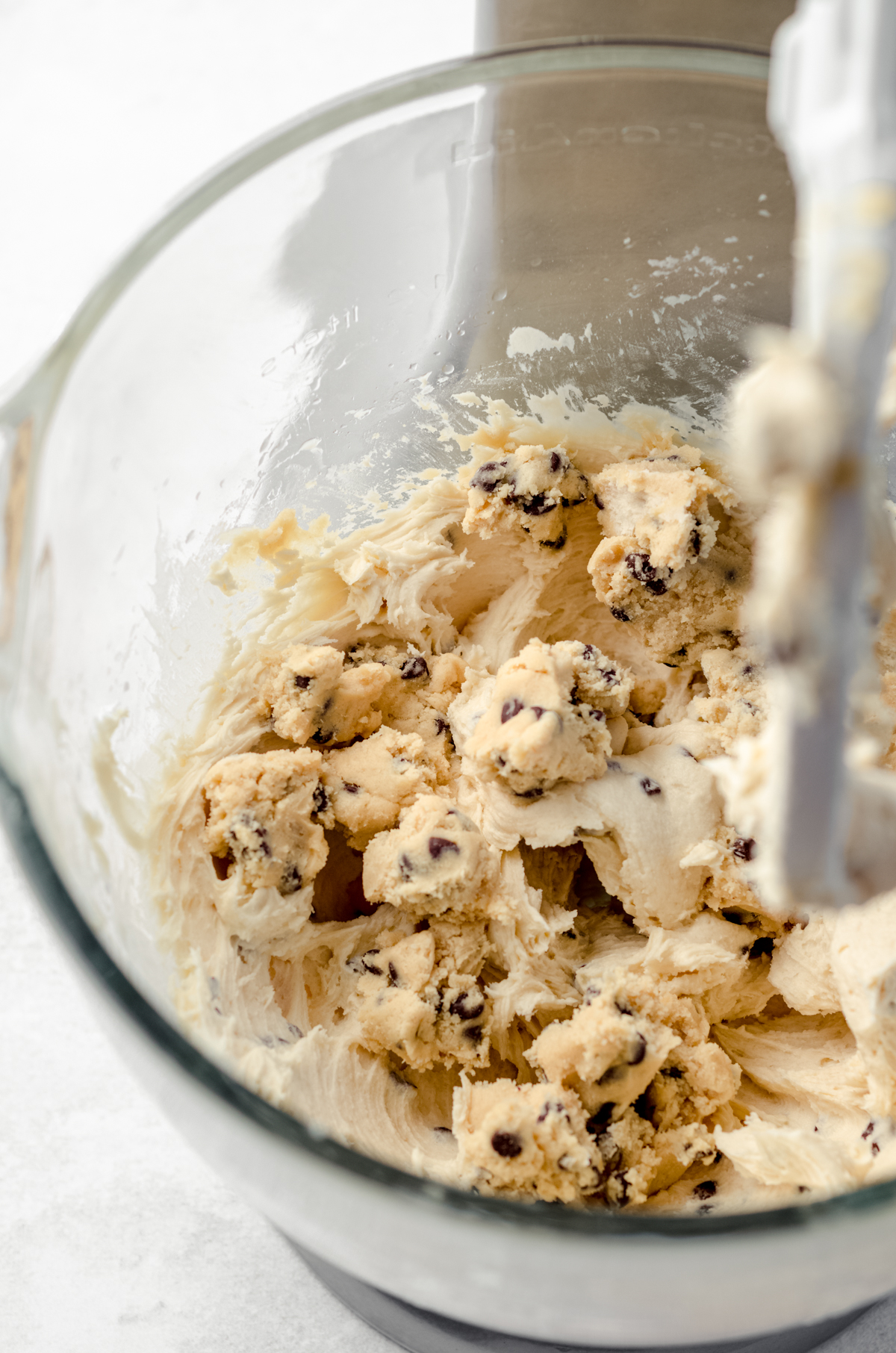 Cookie dough chunks in cookie dough frosting in the bowl of a mixer.