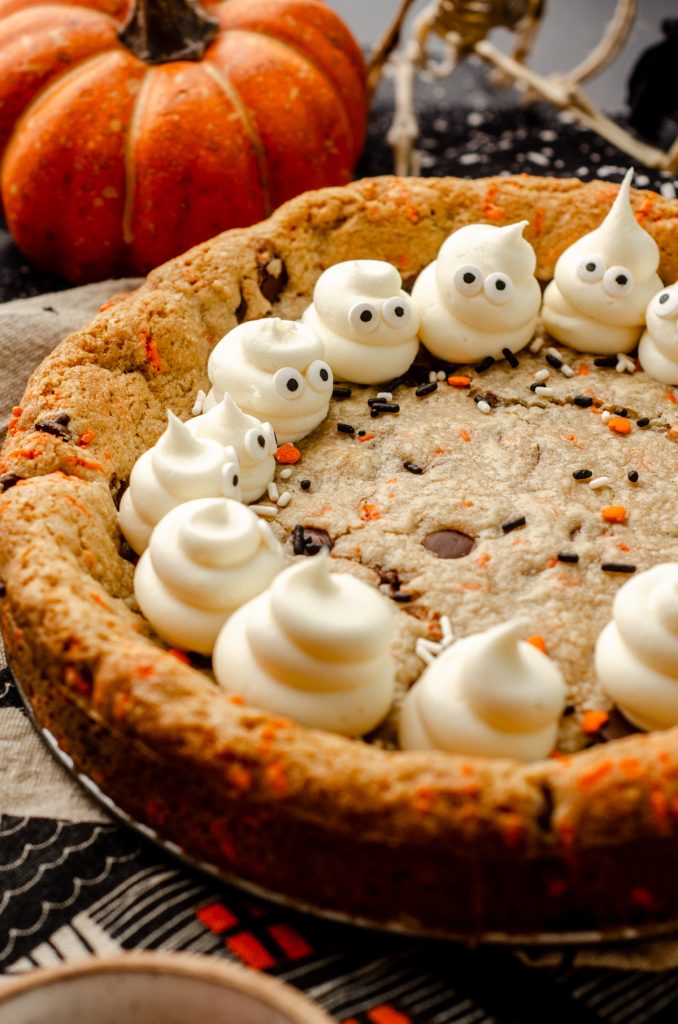 A Halloween cookie cake with buttercream ghosts piped onto the border.
