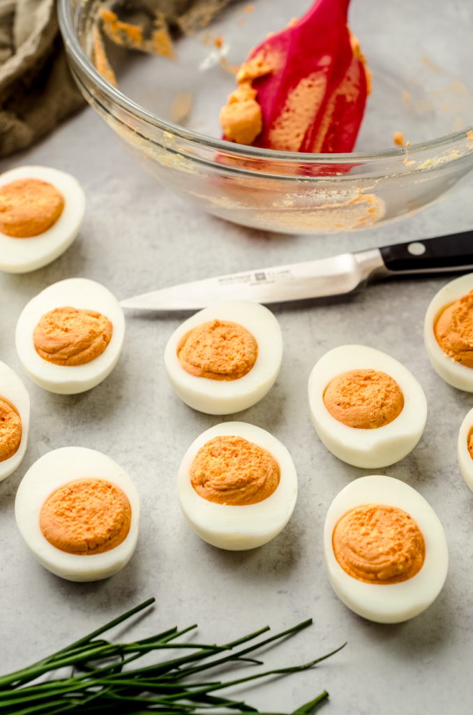 Filled deviled eggs made to look like pumpkins with filling that has been tinted orange.