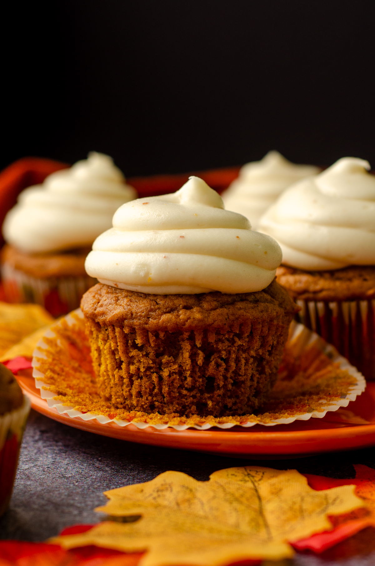 An unwrapped pumpkin cupcake sitting on a plate.
