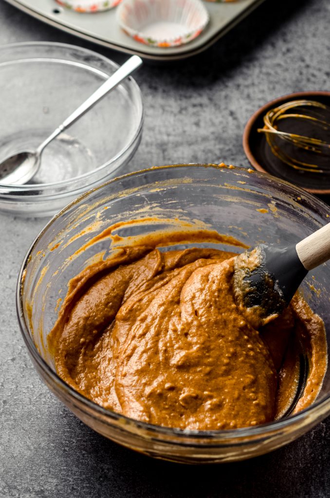 Pumpkin cupcake batter in a large bowl with a spatula.
