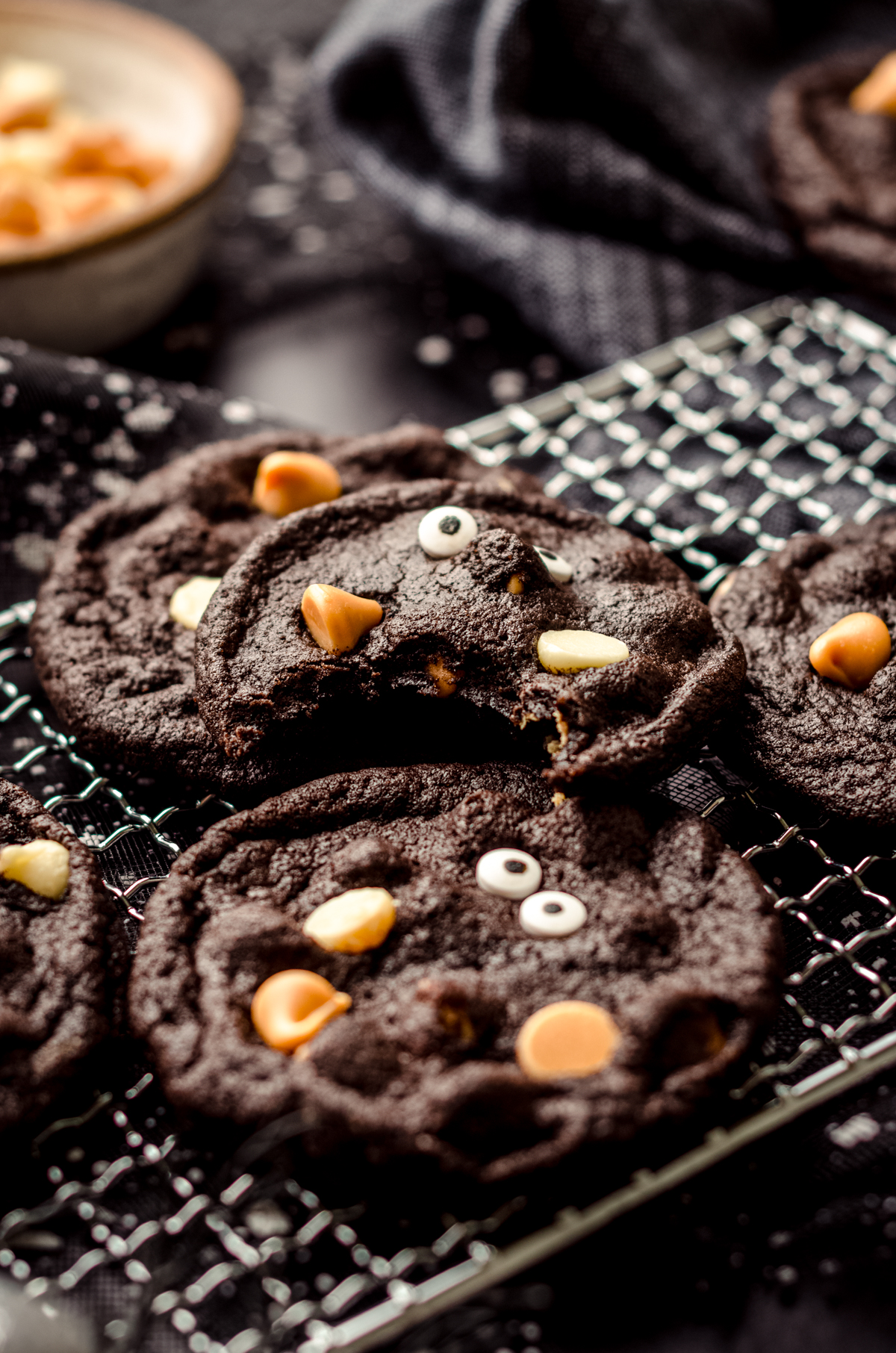 Chocolate Halloween cookies on a cooling rack. A bite was taken out of the one on top.