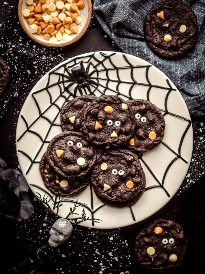 An aerial photo of chocolate Halloween cookies on a spider web plate.