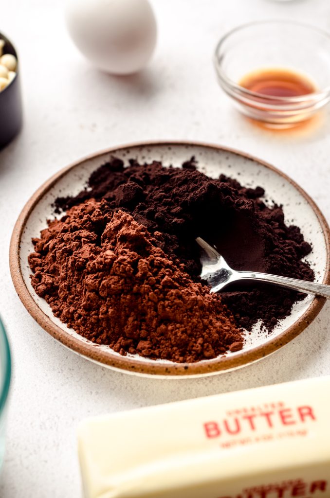 Dutch processed and black cocoa powders on a plate with a spoon.