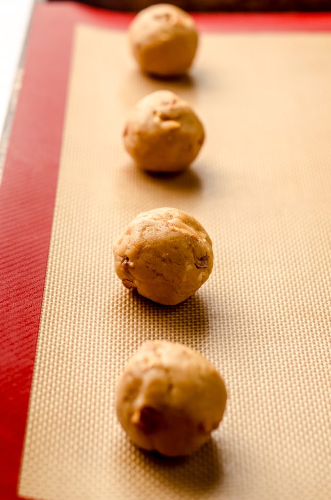 Peanut butter cookie dough balls on a baking sheet ready to bake.