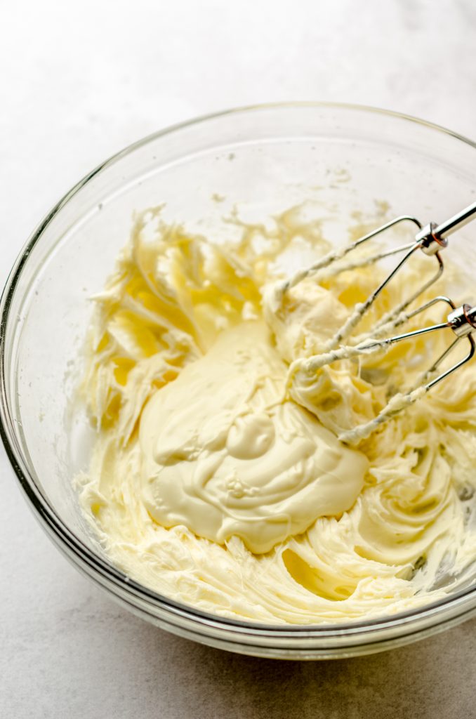 A bowl of butter, powdered sugar, and melted white chocolate mixed together to make frosting.