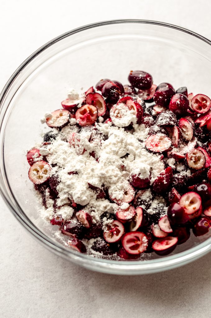 A bowl of chopped cranberries with flour sprinkled on them.