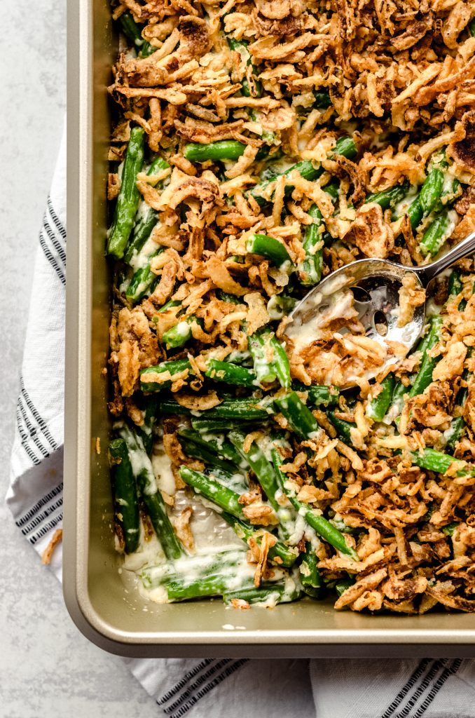 Aerial photo of green bean casserole without mushrooms in a baking dish with a serving spoon.