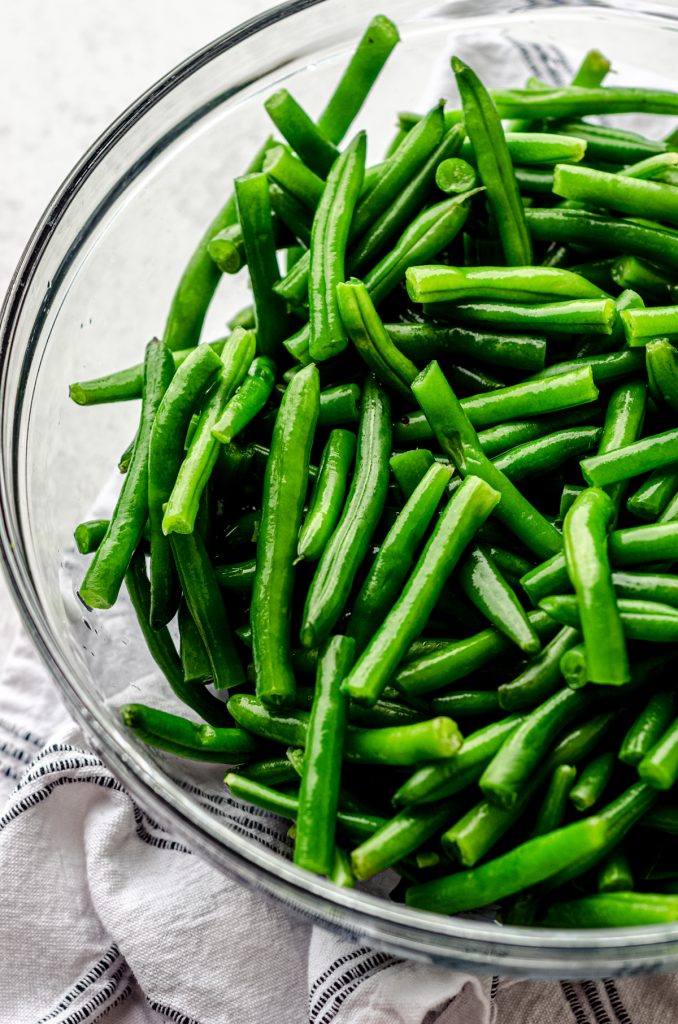 Blanched green beans in a large glass bowl.