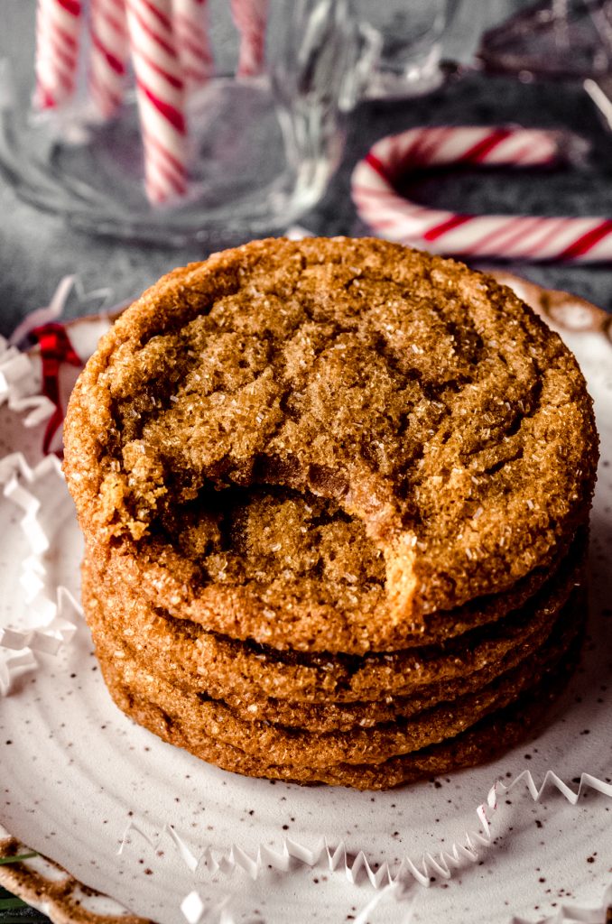 A photo of a stack of chewy gingersnap cookies. A bite has been taken out of the one on the top.