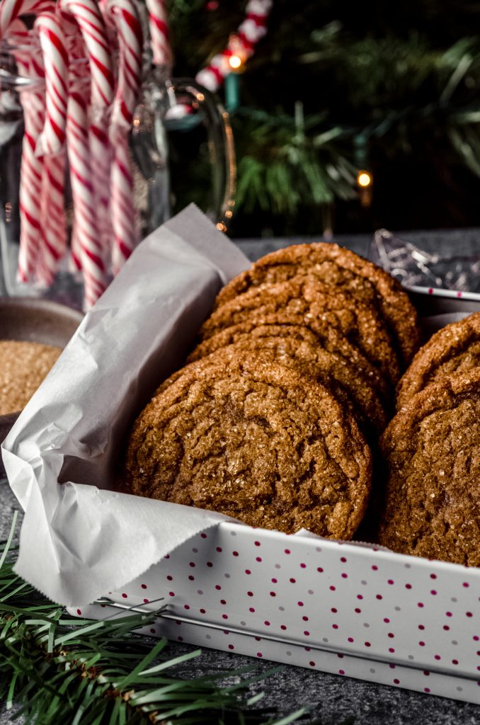 Chewy gingersnap cookies in a cookie tin with parchment paper.