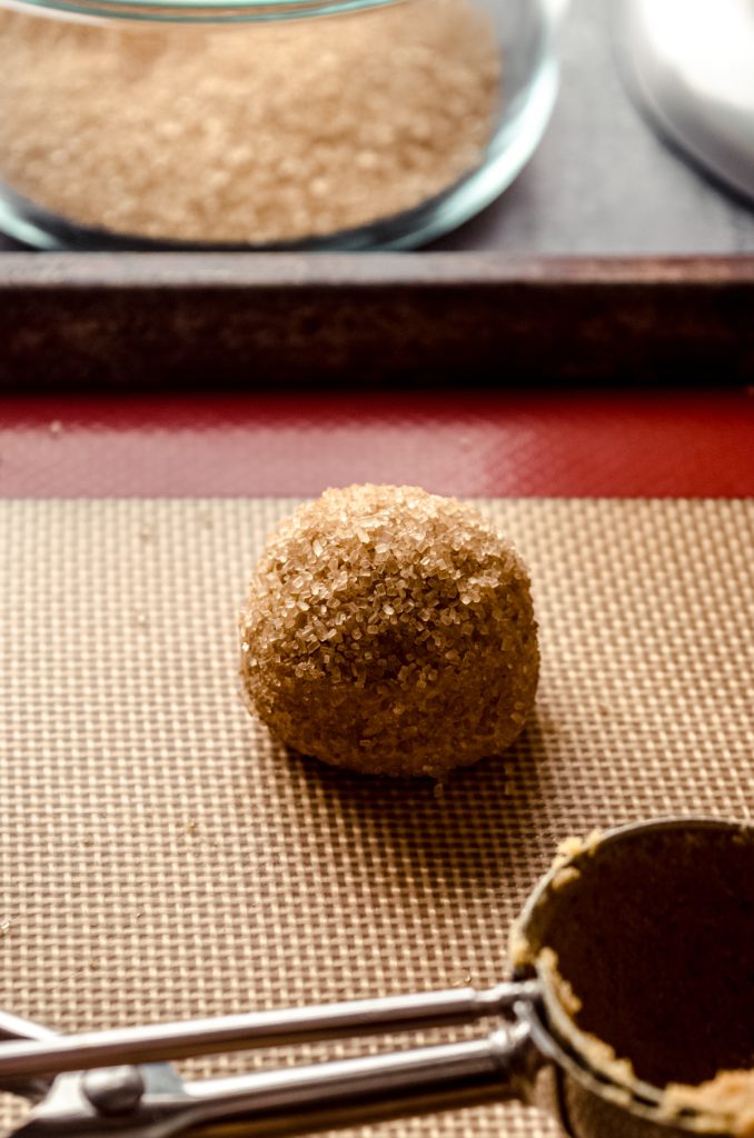 A gingersnap cookie dough ball on a baking sheet.