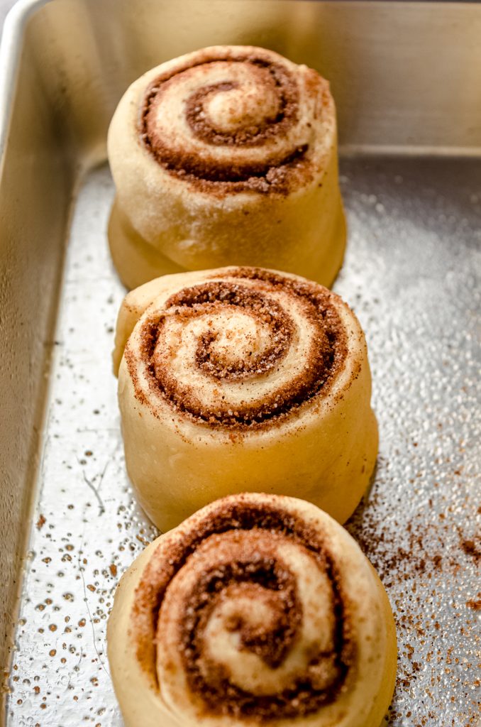 Eggnog cinnamon rolls in a baking dish after rising.