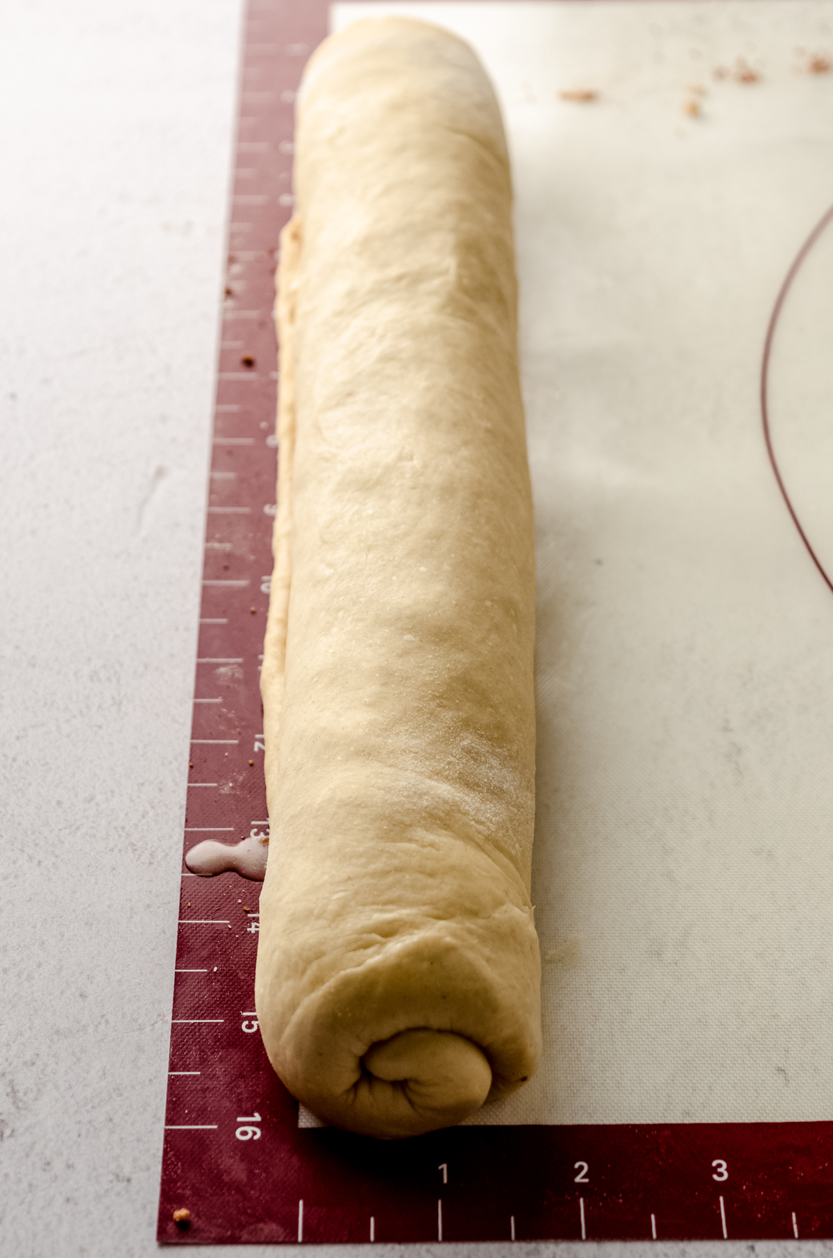 A log of eggnog cinnamon rolls ready to be sliced.