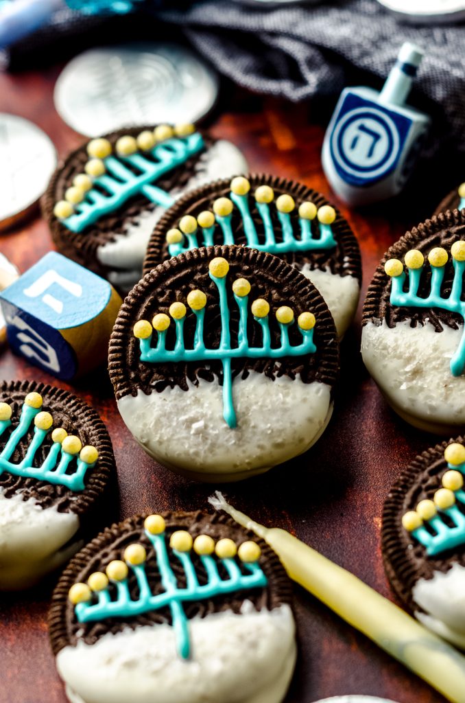 Hanukkah Oreos on a surface surrounded by candles and dreidels.