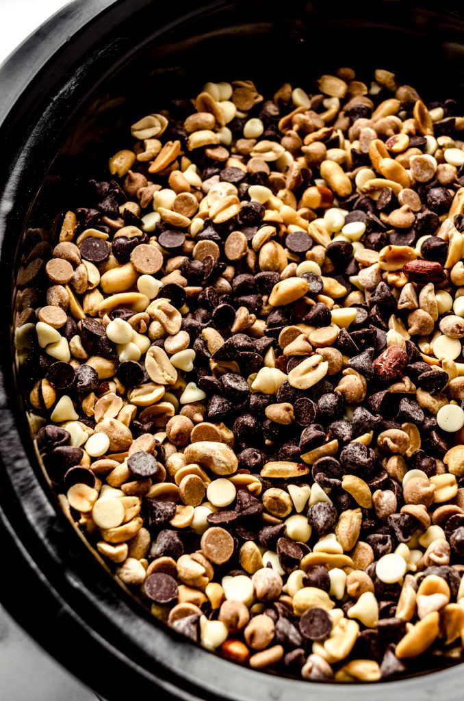 Peanuts, white chocolate chips, peanut butter chips, and semisweet chocolate chips mixed together in a slow cooker.