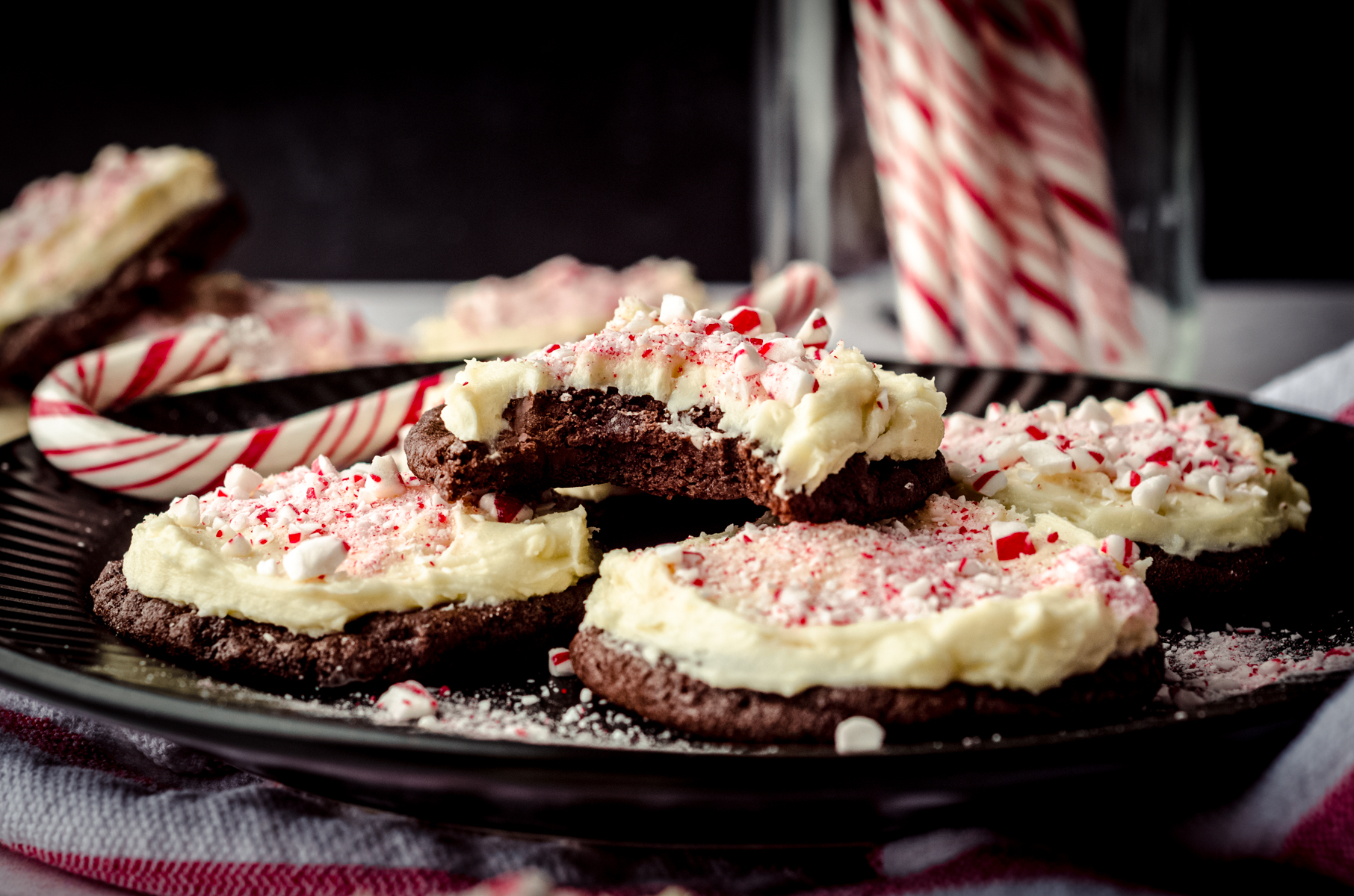 Peppermint bark cookies on a plate. The one on the top has a bite taken out of it.