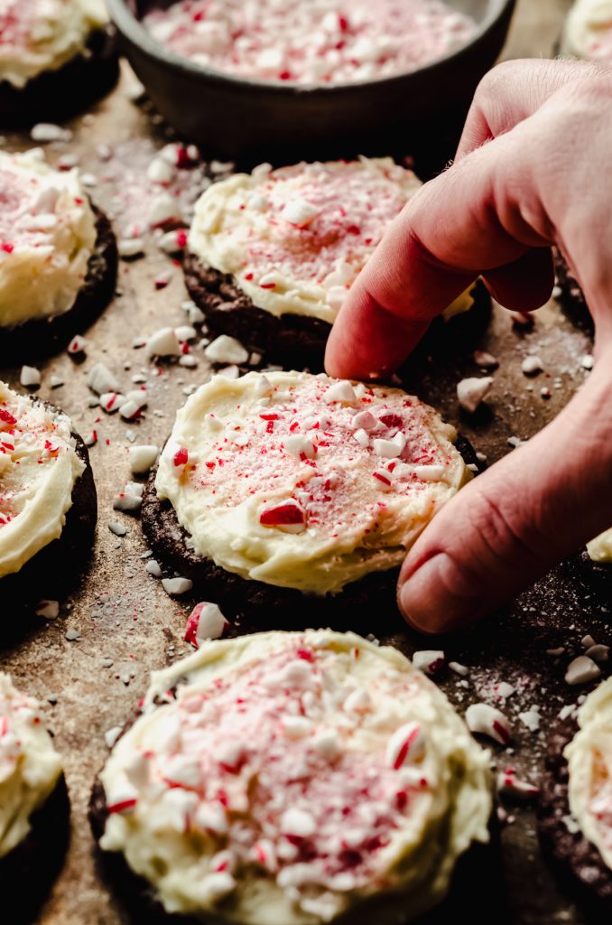 Someone is grabbing a peppermint bark cookie from a baking sheet.