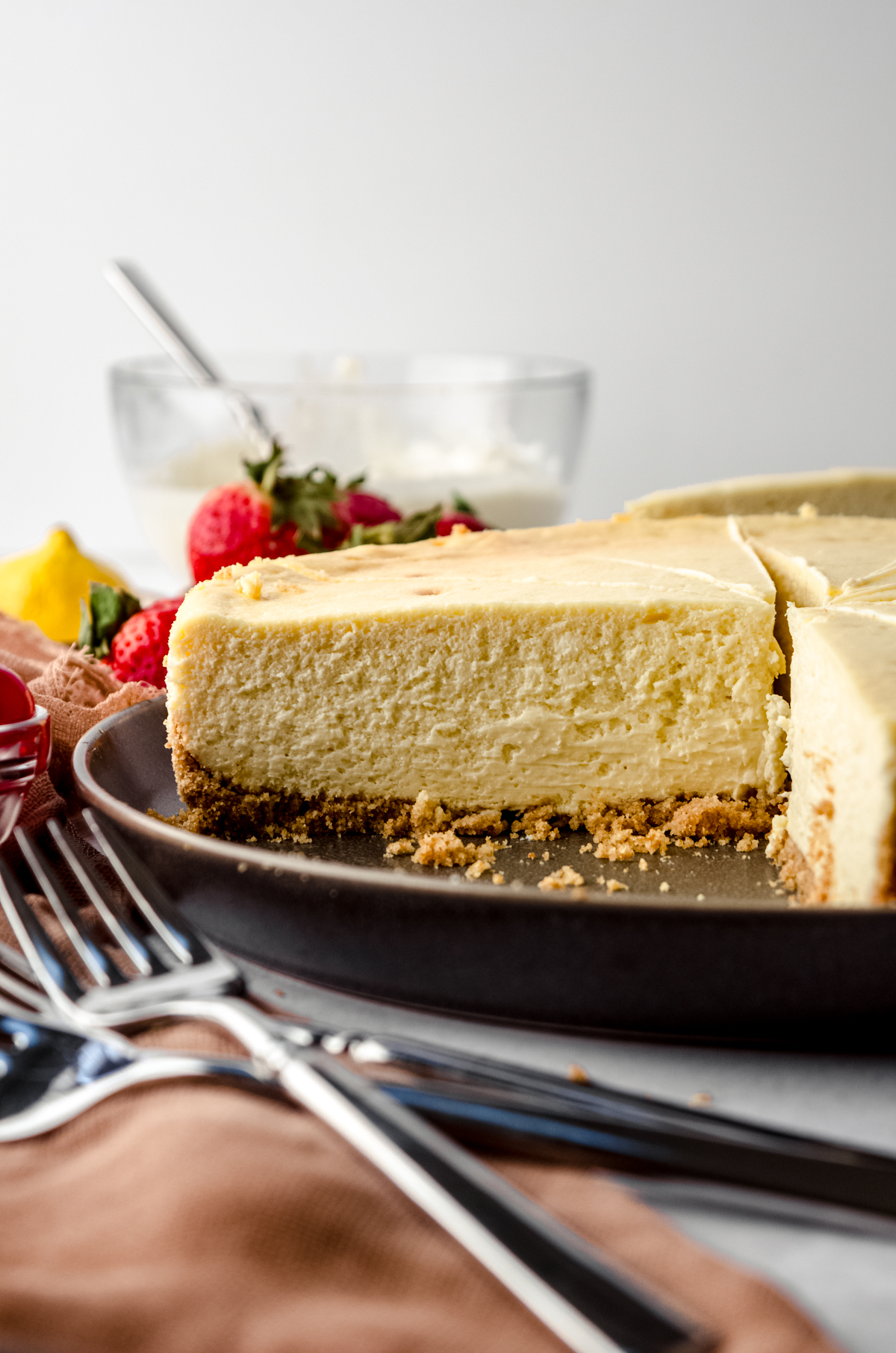 A classic cheesecake on a plate. It has been sliced so you can see the cross-section of the cheesecake.