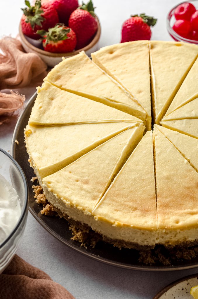A classic cheesecake sliced into pieces on a plate.