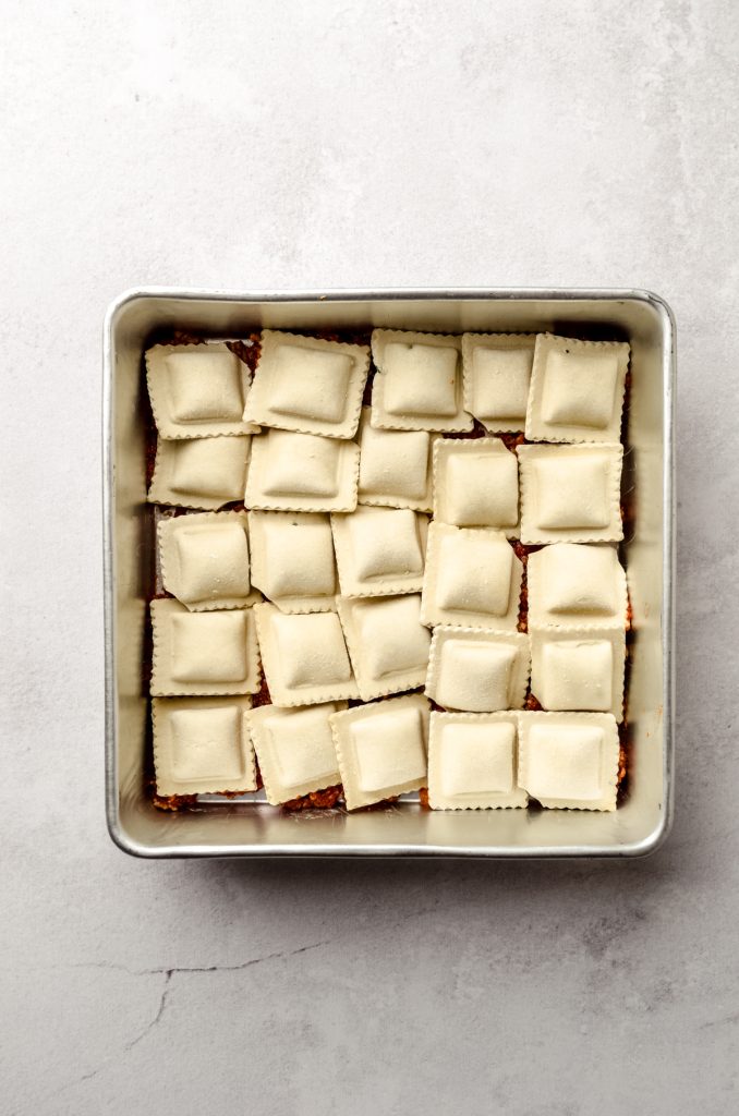 Aerial photo of ravioli lasagna layered into a baking dish.