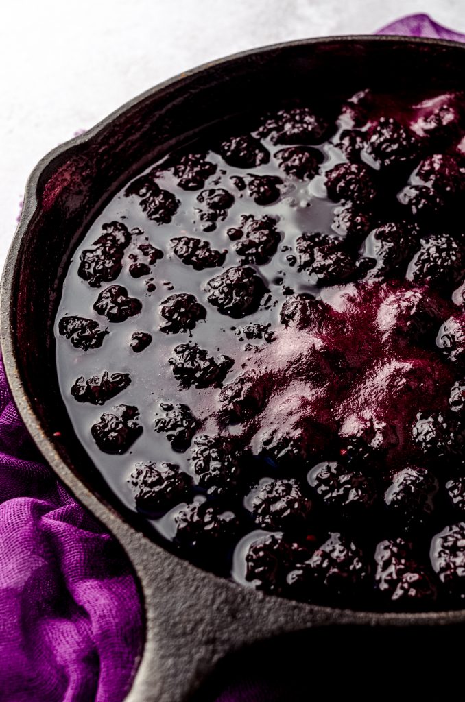 Cooked blackberries for blackberry dumplings in a large cast iron skillet.