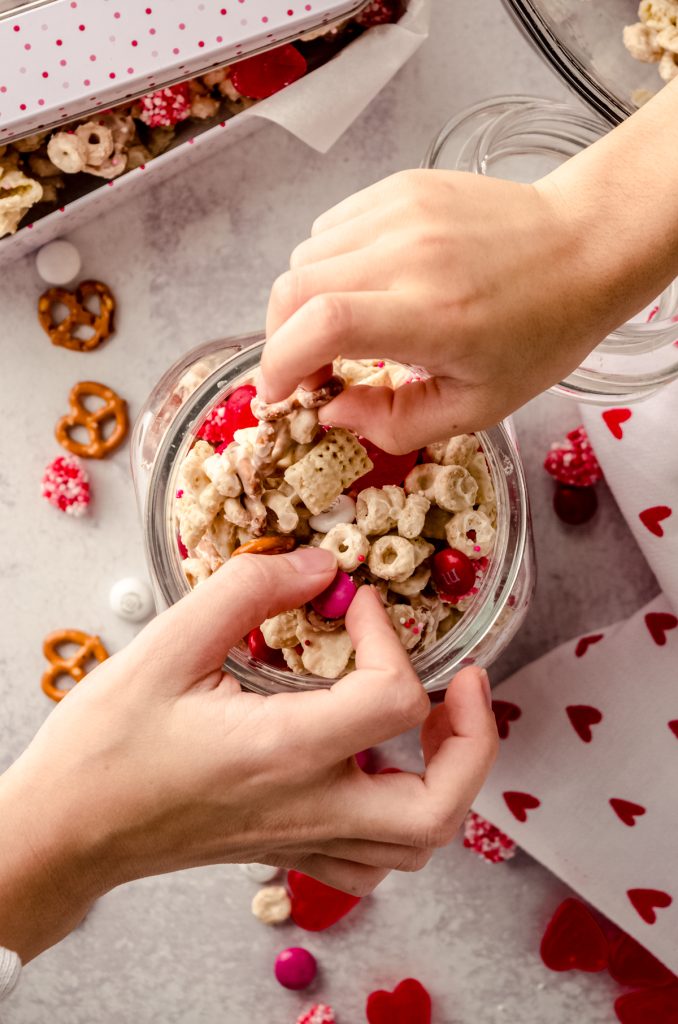 Aerial photo of children's hands grabbing Valentine snack mix from a candy jar.