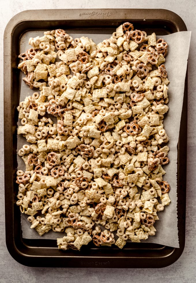 Cheerios, Chex, and pretzels coated in white chocolate on a large baking sheet.