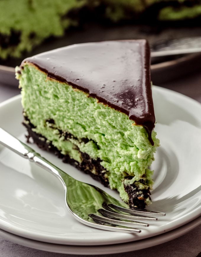 A slice of mint chocolate cheesecake on a plate with a fork.