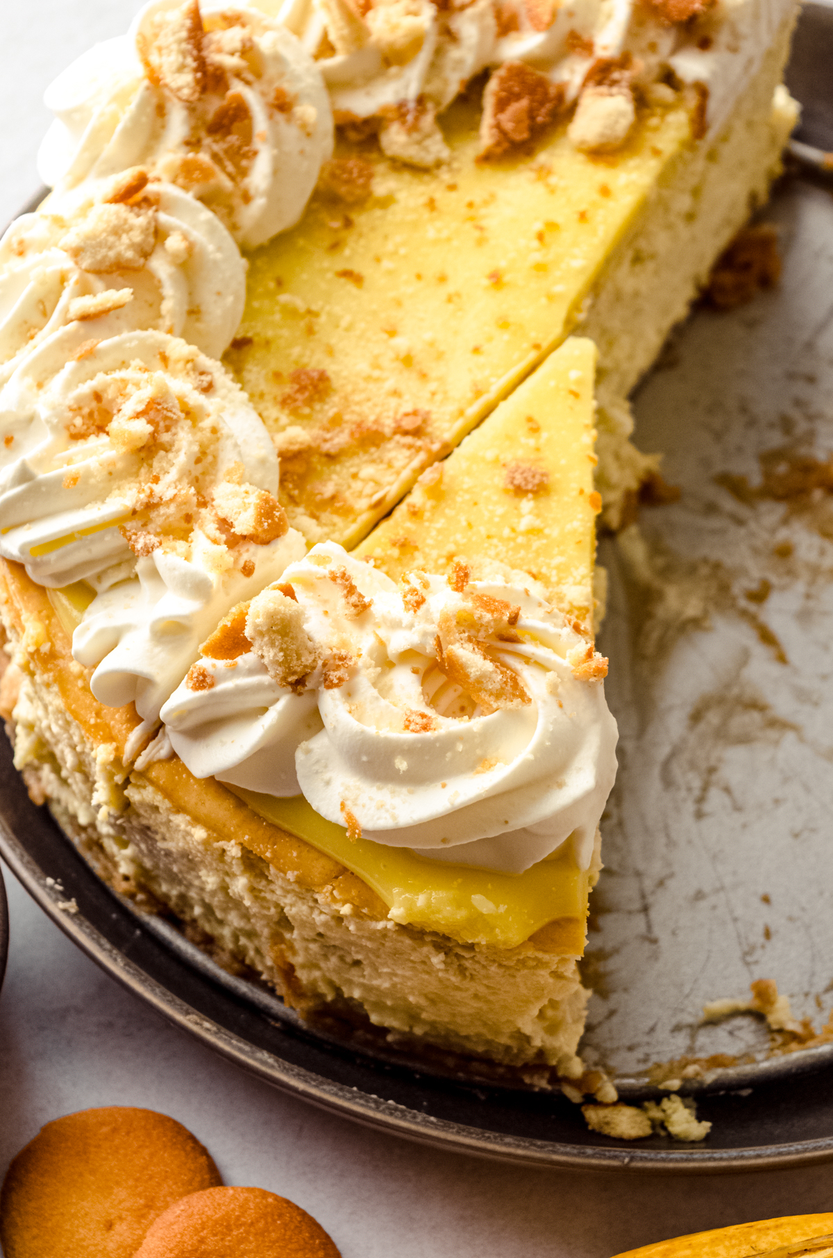 A banana pudding cheesecake on a platter that has been sliced into pieces.