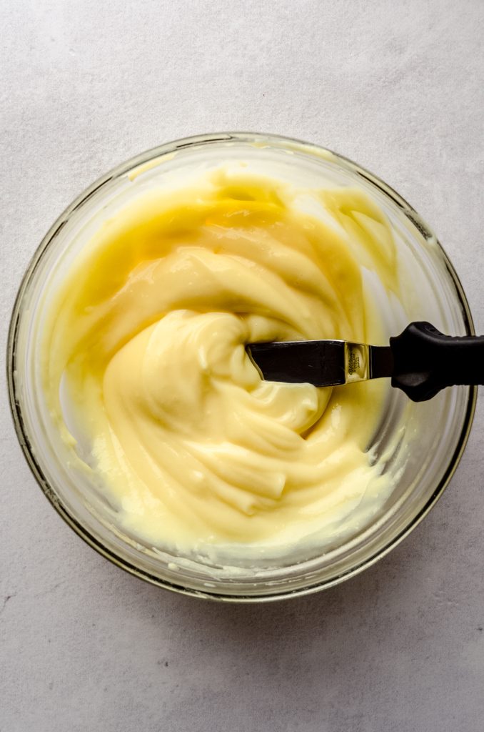 An aerial photo of a bowl of vanilla pudding with an offset spatula in it.