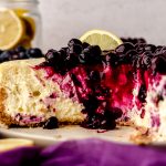 A blueberry lemon cheesecake on a plate that has been sliced so you can see the cross-section.