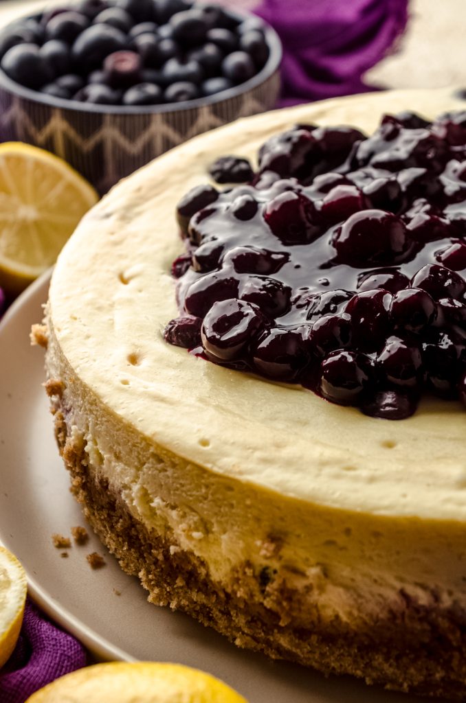 A lemon blueberry cheesecake topped with blueberry sauce on a plate.