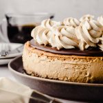 A coffee cheesecake with ganache and coffee whipped cream on top of it.