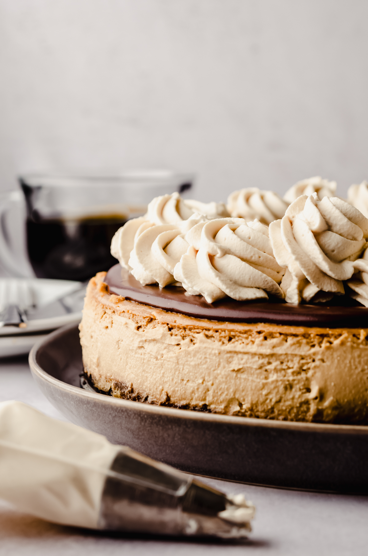 A coffee cheesecake with ganache and coffee whipped cream on top of it.