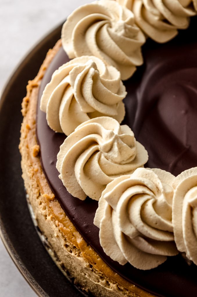 A coffee cheesecake with ganache and coffee whipped cream on top of it.