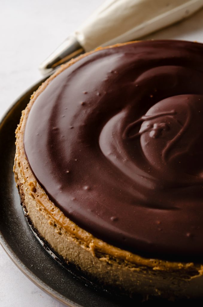 A coffee cheesecake with ganache spread on top of it.