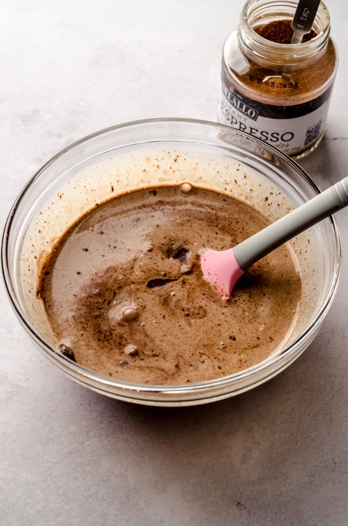 Someone is stirring a bowl of chocolate chips, espresso powder, and heavy cream to make chocolate espresso ganache.