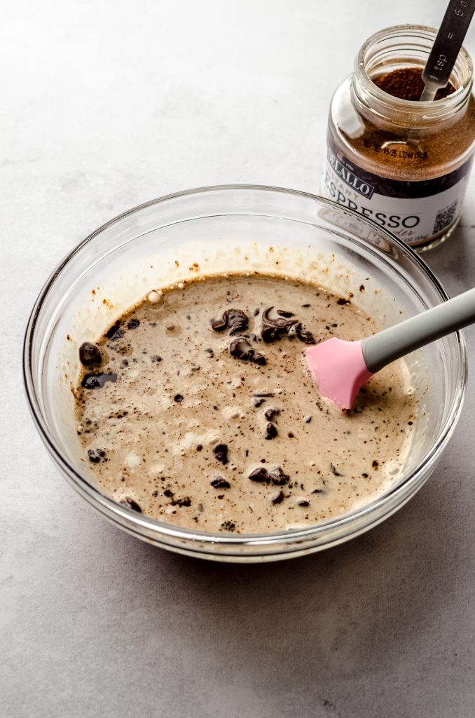 Someone is stirring a bowl of chocolate chips, espresso powder, and heavy cream to make chocolate espresso ganache.