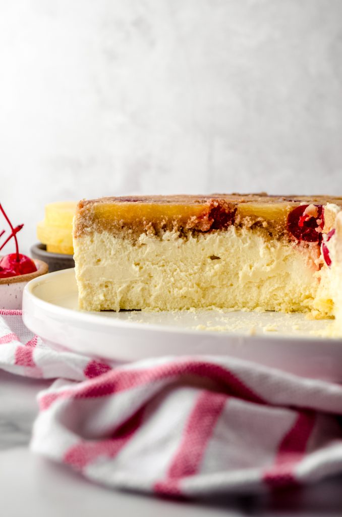 A pineapple upside down cheesecake sitting on a platter and it has been sliced so you can see the cross-section of it.