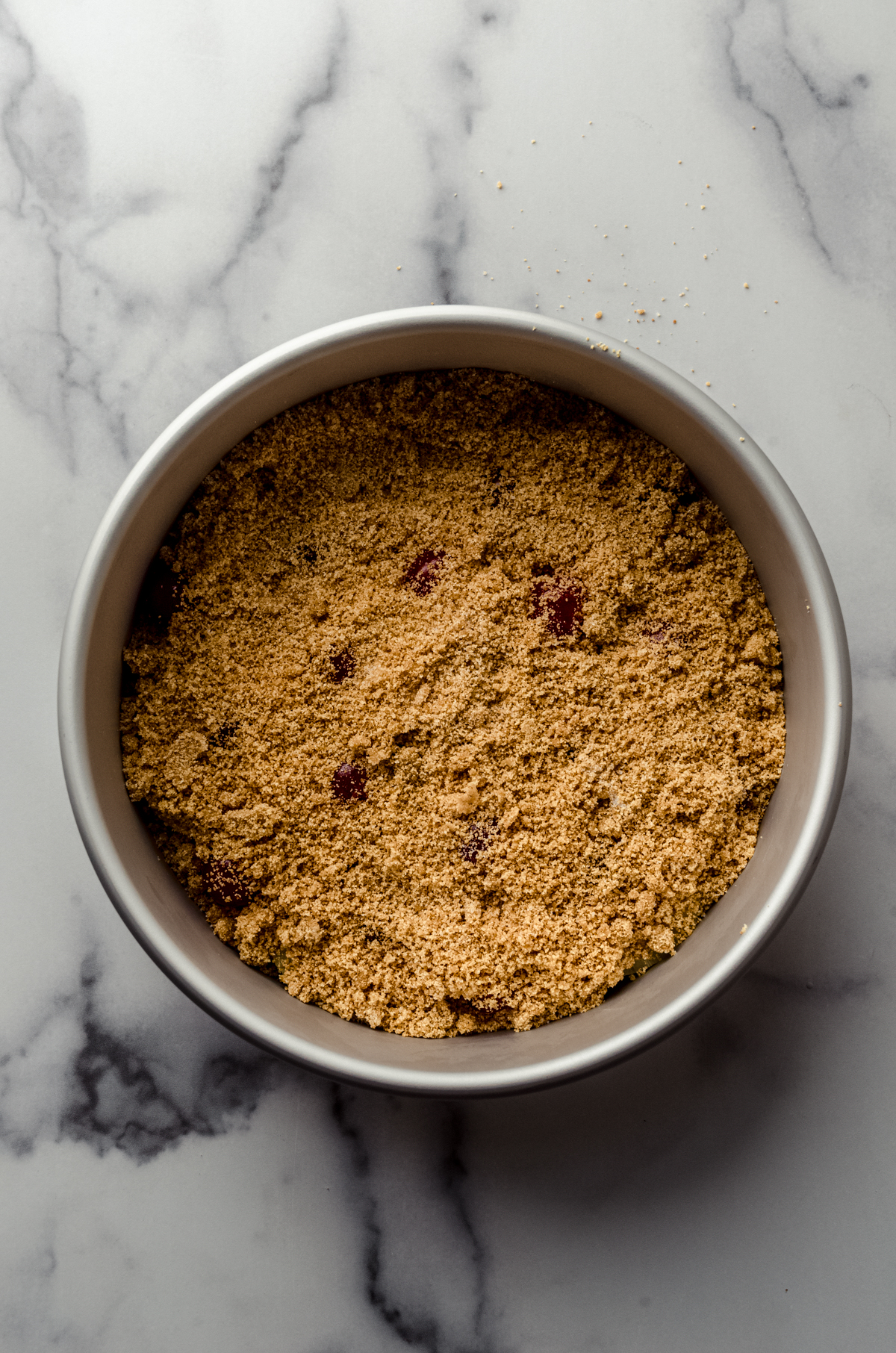 Aerial photo of the graham cracker layer in the bottom of a pan to make pineapple upside down cheesecake.